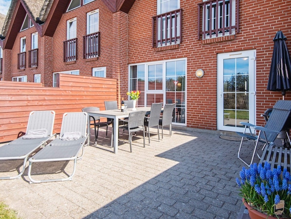 A brick building with a patio area featuring outdoor seating and a potted plant.