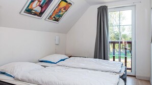 Ein Zimmer mit einem Bett, einem Vorhangfenster und zwei gerahmten Kunstwerken an der Wand.