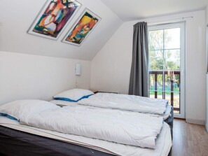 A room with a bed, a window with curtains, and two framed artworks on the wall. - 8 Person Holiday Home in Romo (Rømø)