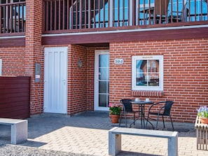 A two-story brick building with a white door, a window with a number '59', outdoor seating with chairs and tables, and a small potted plant. - 8 Person Holiday Home in Romo (Rømø)