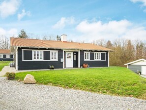A two-story house with a dark exterior, a tiled roof, and a front porch with outdoor seating. - 6 Person Holiday Home in Aabenraa (Aabenraa)