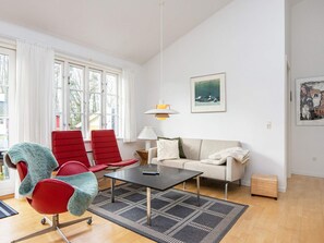 Ein modernes Wohnzimmer mit einer Couch, zwei roten Sesseln, einem Couchtisch und einem Teppich.