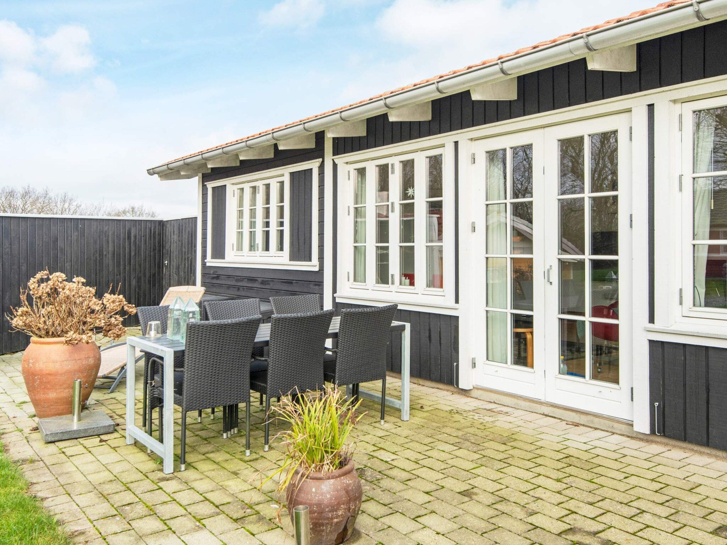 A patio with a table and chairs, a potted plant, and a wooden fence.