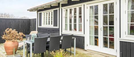 A patio with a table and chairs, a potted plant, and a wooden fence.
