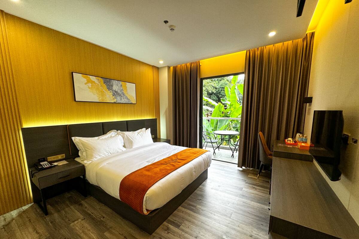 A hotel room with a large bed, a desk, a chair, and a TV.