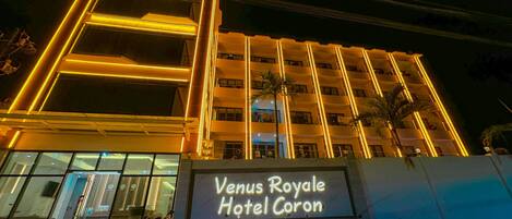 Exterior del Hotel Venus Royale Coron de noche, con líneas verticales iluminadas y un cartel.