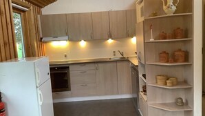 A compact kitchen with wooden cabinets, a white refrigerator, and a shelf with jars. - 6 Person Holiday Home in Bedsted Thy (Bedsted)