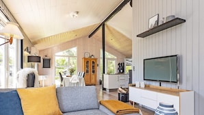 A modern living room with a grey sofa, a wooden coffee table, and a television on a wooden stand. - 4 Person Holiday Home in Vinderup (Vinderup)