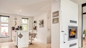 Eine moderne Küche mit einer zentralen Kochinsel, einem eingebauten Kamin und Blick ins Freie.