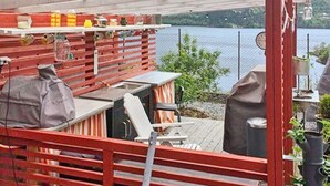 A covered outdoor area with a barbecue setup, seating, and a view of a body of water. - 4 Star Holiday Home in Bruvik (Masfjorden)