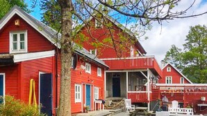 A red wooden building with a porch, a tree in front, and gravel ground. - 4 Star Holiday Home in Bruvik (Masfjorden)