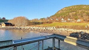 Un muelle a la orilla del río con barandilla de metal, pared de piedra y plataforma de madera que se adentra en el agua.