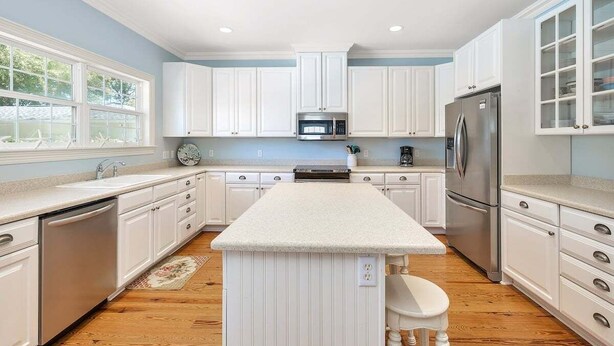A kitchen with white cabinets, stainless steel appliances, and a central island. - 4324 10th Street East Beach (Saint Simons Island)