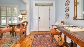 A dining area with a wooden table and chairs, a patterned rug, and a white door with a small window above it. - 4324 10th Street East Beach (Saint Simons Island)