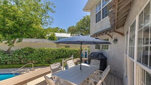 A wooden deck with a pool table and chairs, a barbecue grill, and a large umbrella. - 4324 10th Street East Beach (Saint Simons Island)