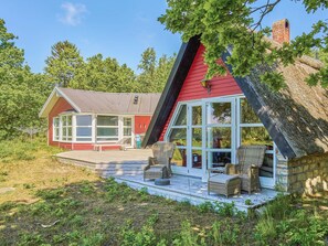 A house with a red exterior, large windows, and a porch with wicker furniture. - 4 Star Holiday Home in Aakirkeby (Akirkeby)