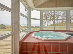 A spa area with a hot tub, large windows, and a view of the sea. - 4 Star Holiday Home in Aakirkeby (Akirkeby)