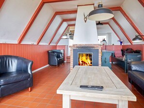 A cozy room with a fireplace, leather sofas, and a wooden table. - 4 Star Holiday Home in Aakirkeby (Akirkeby)