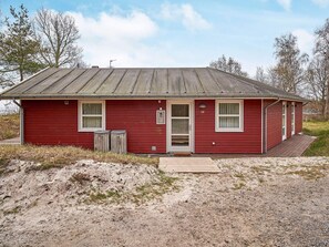 A red single-story building with a metal roof, a front door, and two windows. - 4 Star Holiday Home in Aakirkeby (Akirkeby)