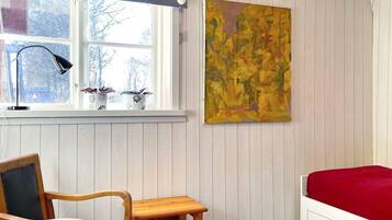 A room with a bed, a desk, a chair, a window with blinds, a lamp, and a painting.
