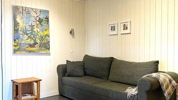 Una sala de estar con un sofá gris, una mesita de madera y un cuadro en la pared.