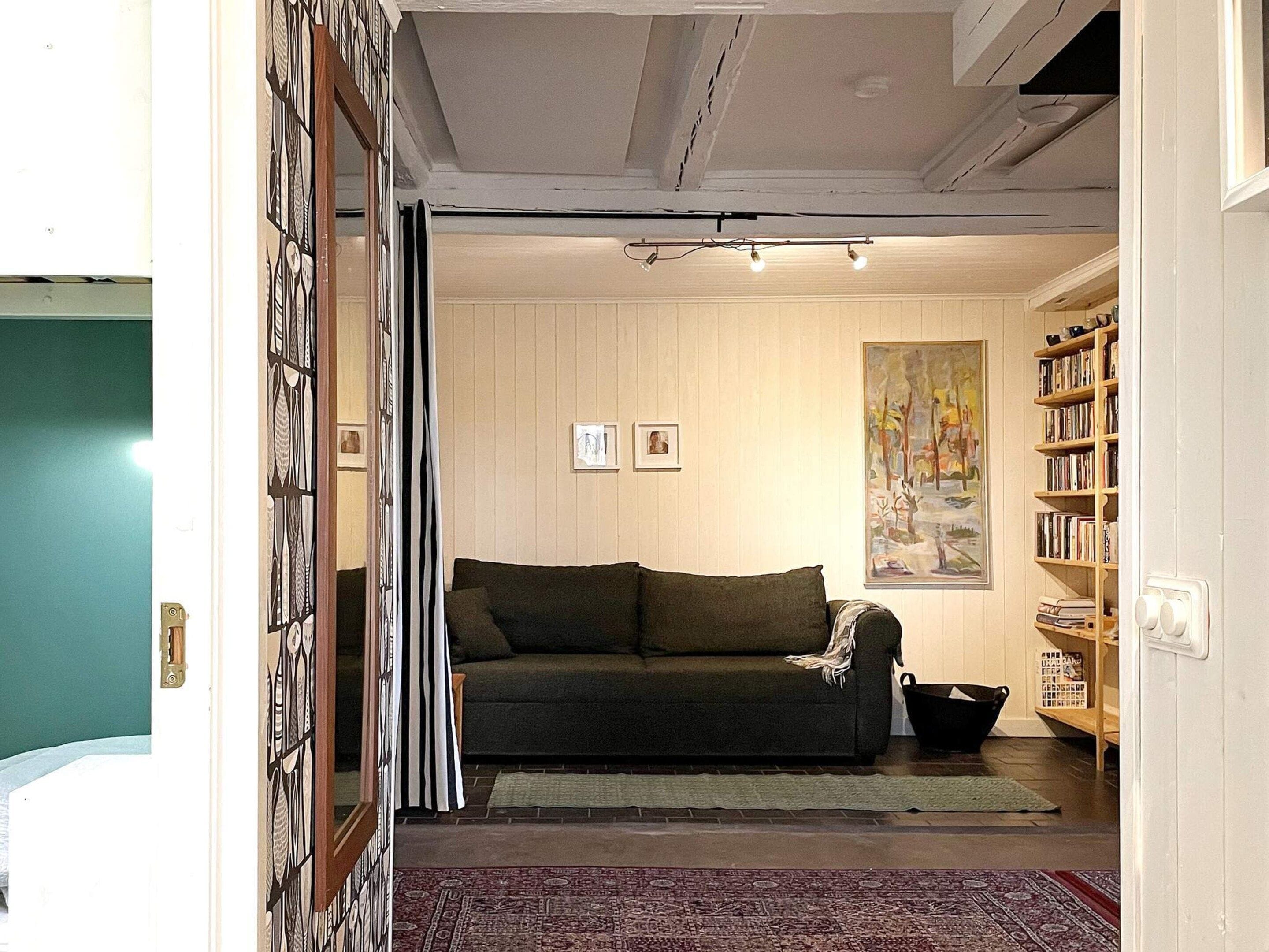 A living room with a sofa, a painting, and a bookshelf.
