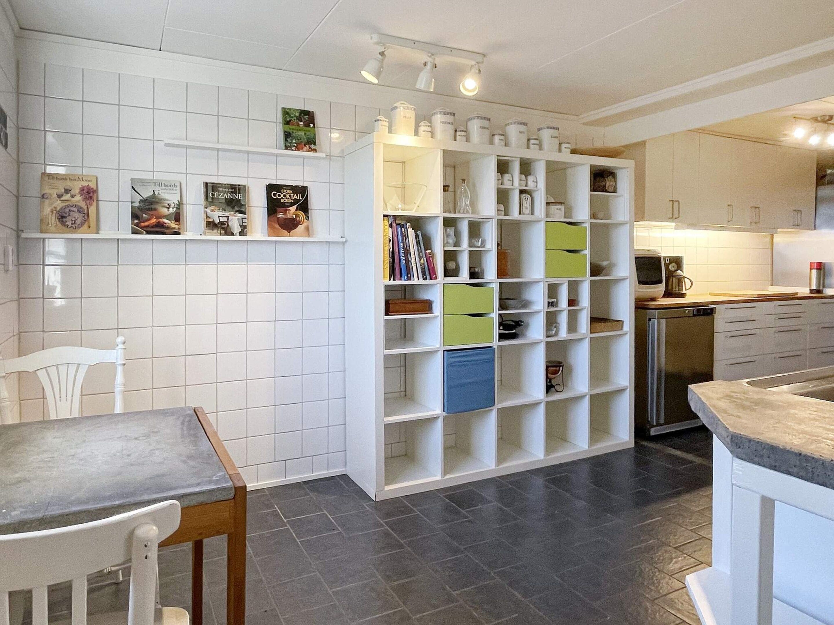 A kitchen with white cabinets, a built-in bookshelf, and a dining area with a table and chairs.