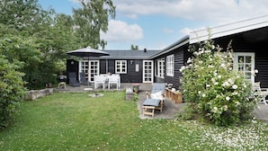 A black wooden house with a patio area, a barbecue grill, and outdoor seating. - 4 Person Holiday Home in Helsinge (Helsinge)