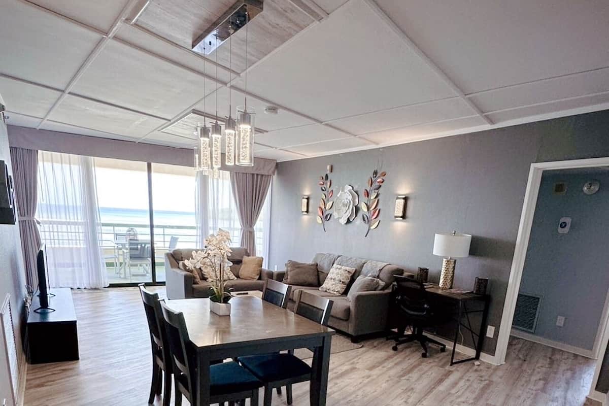 Una sala de estar moderna con comedor, ventanas amplias y vistas al exterior.