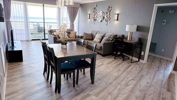 A modern living room with a dining area, large windows, and a view of the outdoors.