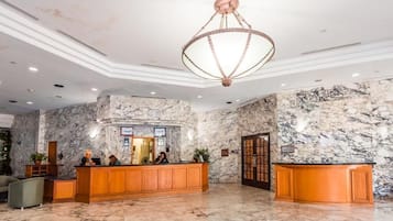 A lobby with marble walls, a reception desk, and a chandelier.
