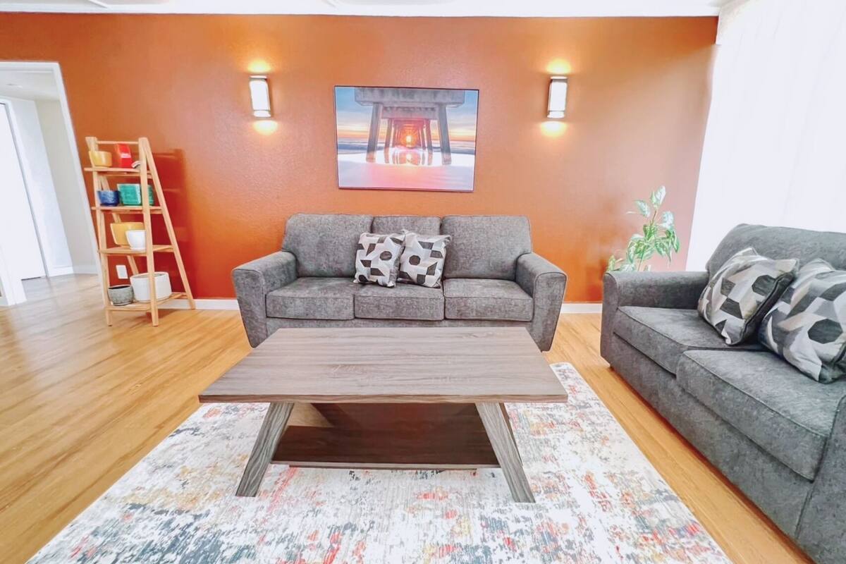 Una sala de estar con un sofá gris, una mesa de centro de madera y una alfombra colorida.