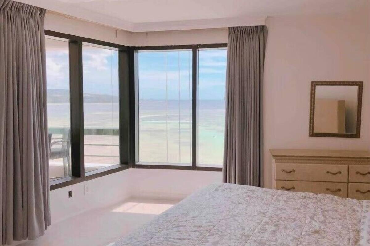 Un dormitorio con un gran ventanal que ofrece vistas a la playa y al océano.