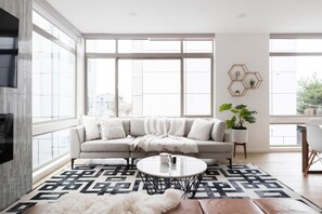 Uma sala de estar moderna com uma grande janela, um sofá, uma mesa de centro e um vaso com planta.