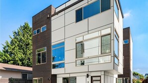 Ett modernt hus i två våningar med stora fönster, en mörkbrun exteriör och en vit fasad.