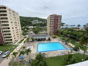 A hotel with a swimming pool surrounded by palm trees and lounge chairs. - Turtle Beach Towers Vacation  (Ocho Rios)