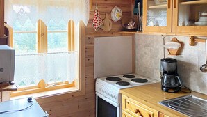 A compact kitchen with a stove, coffee maker, and wooden cabinets. - 4 Person Holiday Home in Hardbakke (Solund)