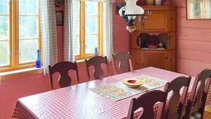 A dining area with a checkered tablecloth, wooden chairs, and a window with curtains. - 4 Person Holiday Home in Hardbakke (Solund)