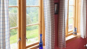 A room with large windows, a wooden bench, a blue vase, and a pitcher on the windowsill. - 4 Person Holiday Home in Hardbakke (Solund)
