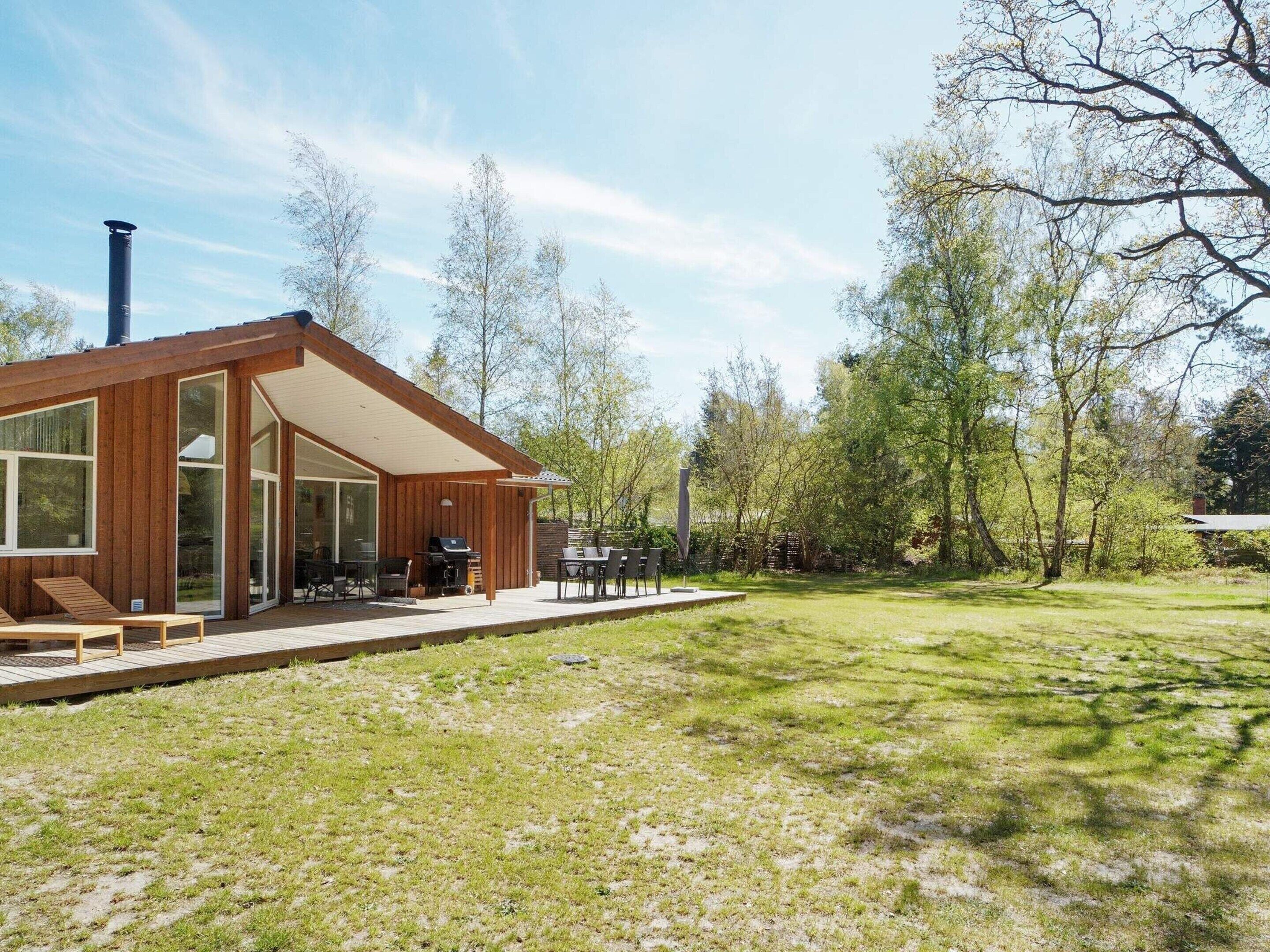 A modern house with a large deck, a barbecue area, and a spacious outdoor seating area.