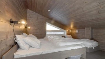 A bedroom with a wooden sloped ceiling, a bed with white bedding, and a skylight.