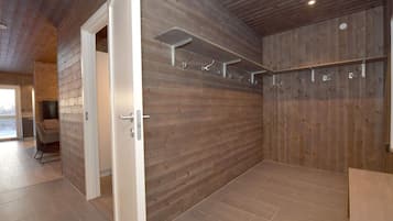A room with wooden walls, a tiled floor, and a door leading to another space.