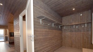 Une salle de bain moderne avec des murs en bois, un espace douche et une porte visible donnant sur une autre pièce.