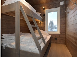 A wooden cabin room with a bunk bed, a window with a snowy view, and a wall-mounted light fixture. - 4 Star Holiday Home in Idre (Idre)