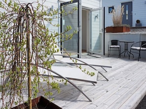 A deck with a glass door, a small table with chairs, and a potted plant. - 2 Person Holiday Home in Marstrand (Marstrand)