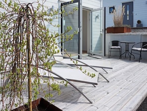 An outdoor deck with a glass door leading to a room, a small table with chairs, and a potted plant. - 2 Person Holiday Home in Marstrand (Marstrand)