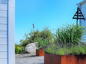 A garden with a large rock, a metal fence, and a building with a triangular structure. - 2 Person Holiday Home in Marstrand (Marstrand)