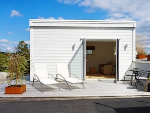 A modern, single-story building with a white exterior, a glass door entrance, and a patio area with outdoor furniture. - 2 Person Holiday Home in Marstrand (Marstrand)