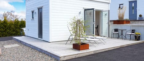 A modern, single-story building with a flat roof, a small porch area, and a potted plant.