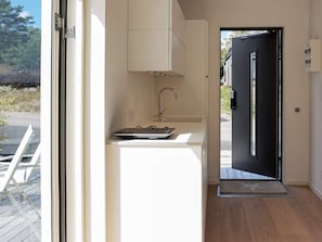 A modern kitchen with a built-in sink, a laptop on the countertop, and a black door leading outside. - 2 Person Holiday Home in Marstrand (Marstrand)